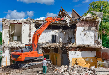 Fototapeta premium Baumaschine im Einsatz - Abbrucharbeiten an einem Haus