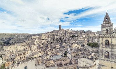 Fototapeta na wymiar panoramic view of typical stones (Sassi di Matera) and church of Matera under blue sky