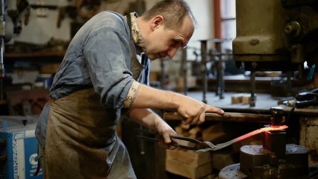 blacksmith forges iron on the anvil