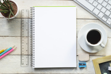 An empty page of a notebook in the center of a white wooden table at coffee time. Empty copy space for Editor's text.