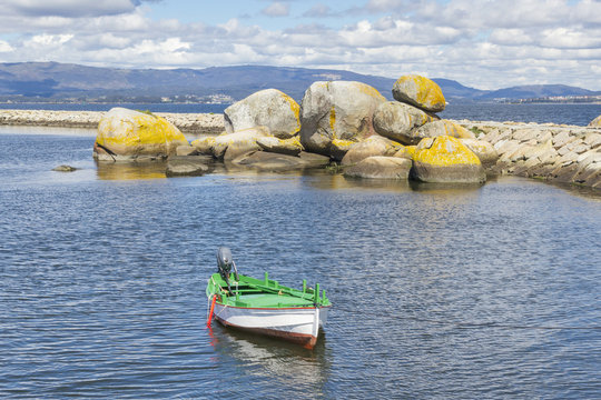 White fishing boat dorna and rocks