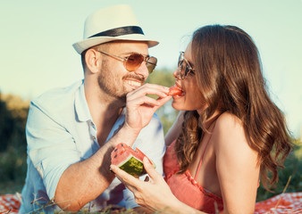Happy couple on a picnic eating watermelon
