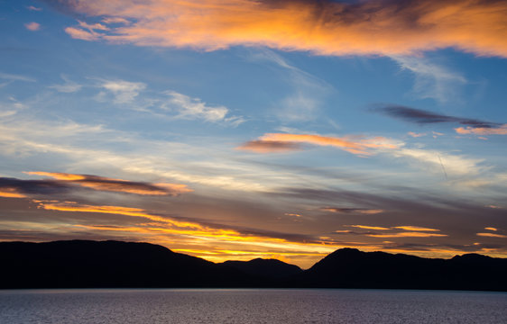 View from the cruise ship sailing in the inside passage of Southwest Alaska as sun sets behind the mountains.