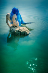 Meerjungfrau auf Stein am Wasser