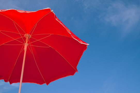 Red beach umbrella and blue sky. Summer beach vacations