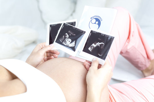 Portrait schwangere Frau liegend betrachtet Ultraschallbilder