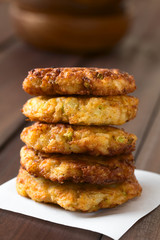 Rice patties or fritters made of cooked rice, carrot, onion, garlic and celery stalks arranged in a pile, photographed with natural light (Selective Focus, Focus on the front of the patties)