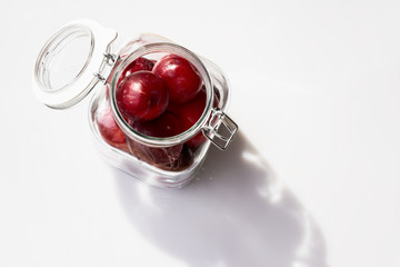 Plums in a glass jar on a white background