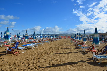 endlose Reihen von Sonnenschirmen und Liegen an italienischem Sandstrand