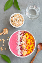 Strawberry smoothie bowl topped with mango, granola, pomegranate and shredded coconut. Top view