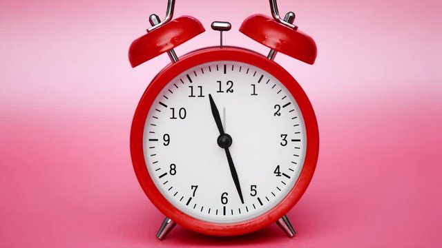 Red vintage alarm clock on pink pastel background timelapse. Bright stylized colors.
