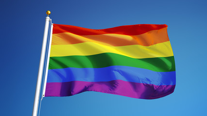 The gay pride rainbow flag waving against clean blue sky, close up, isolated with clipping path mask alpha channel transparency
