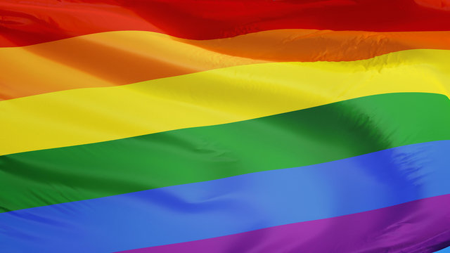 The gay pride rainbow flag waving against clean blue sky, close up, isolated with clipping path mask alpha channel transparency