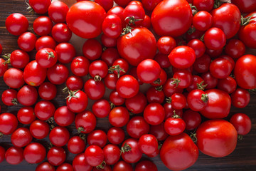 Tomatoes and cherry tomatoes on a wooden background