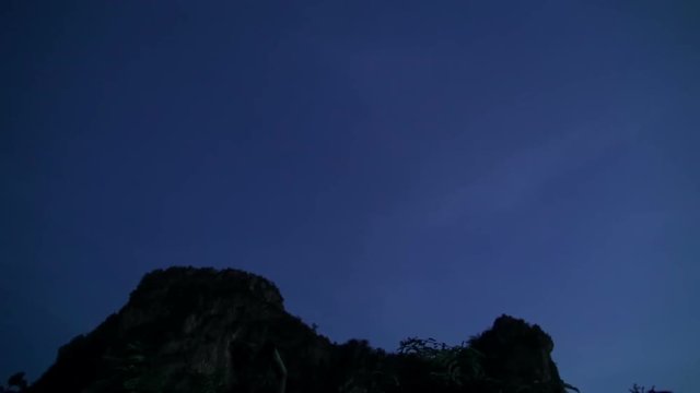 Thousands of bats swarm from a cave at dusk. Time lapse