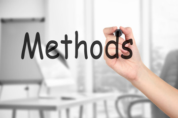 Human hand writing word METHODS at transparent whiteboard on conference hall background