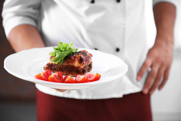 Chef cook holding meat dish, close up