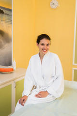 Beautiful young woman in a spa dressed in white terry cloth robe waiting for massage.