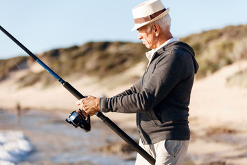 Senior man fishing at sea side