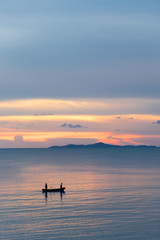 Fototapeta na wymiar Silhouette of human row on the boat in ocean sea over dramatic s