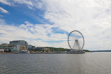 Panorama of National Harbor with Ferris on the pier, Maryland, USA. National Harbor waterfront under blue skies with scenic clouds.