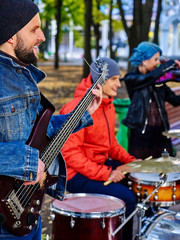 Group of music street performers with girl violinist on autumn outdoor. Music people play drums.
