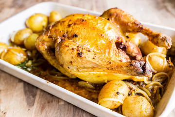 roasted curry chicken with potatoes in a plate on an old oak table with focal blur