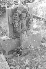 Black and white photo headstone with a cross and an angel face.