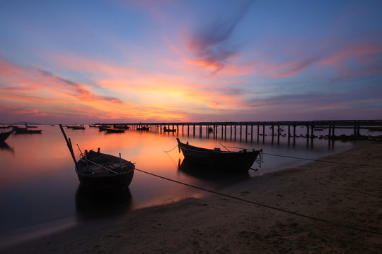 Silhouette natural background of small fishing boats moored beached on the beach during time the sunset and the beautiful natural of the colorful sky at Bang Phra beach , Chonburi province in Thailand
