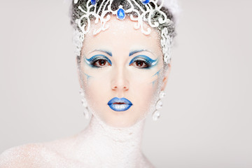 Beautiful girl with creative make-up for the new year. Winter portrait. Bright colors, blue lips, elegant dress design hair. Conceptual art. Snow Queen.