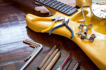 yellow electric guitar on wood in repair & luthier workshop, fixing & musical instrument repairing...