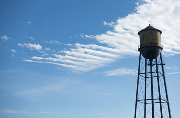 Old Watertower Isolated Against Blue and White Sky
