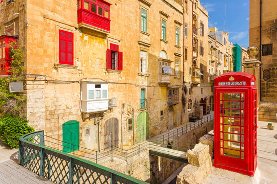 Valletta, Malta - Streetview with traditional british red phone box and red Maltese balconies 
