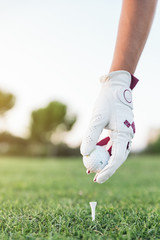 Hand woman putting a golf ball on the tee.