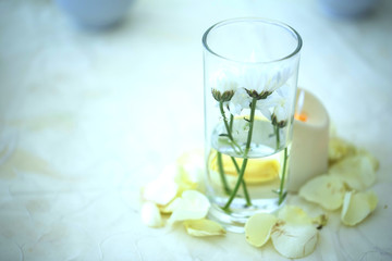 Glass of water with small flowers inserted.