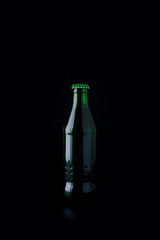 Green bottles with drink on black background.