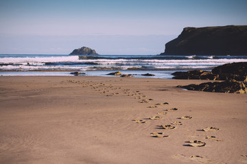 Footprints in the sand on Polzeath beach Vintage Retro Filter.