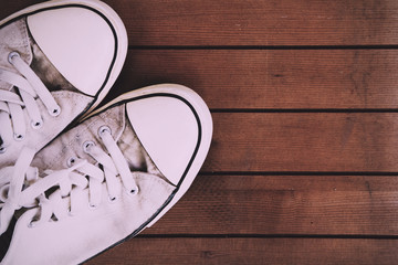 Old canvas shoes on a wooden floor Vintage Retro Filter.