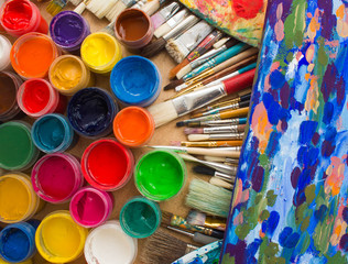 Colorful paints, brushes, palette on the wooden background. The workplace of the artist. Banner for the school.