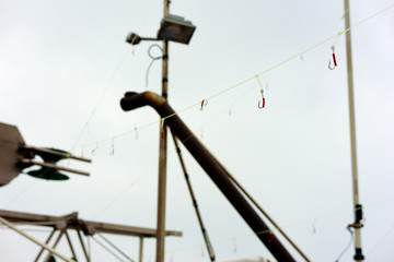 Fishing line on boat with lots of hooks. Narrow focus on one hook the rest are blurred. Weather is misty and damp.