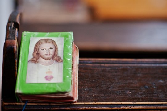 Prayer book with Jesus Christ on cover at bench in church