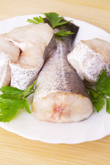 pieces of hake on the plate on wood