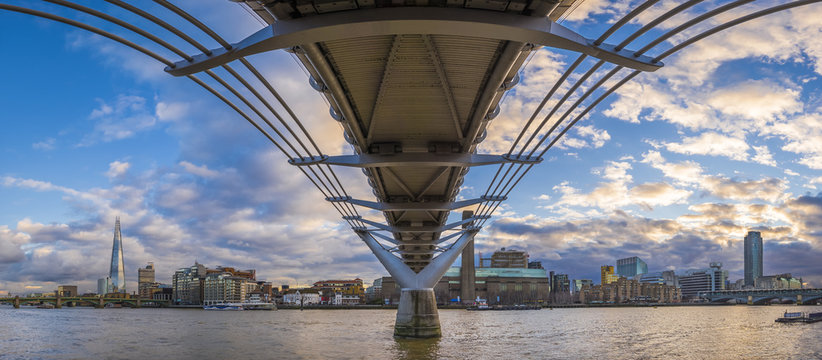 Panoramic skyline taken under the Millennium Bridge at sunset with beautiful sky and clouds - London, UK