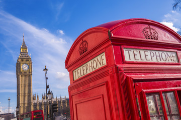 London, UK - Iconic British red telephone box with Big Ben and Double Decker bus at background on a sunny day with blue sky