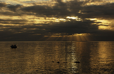 Sunrays over bay with small boat