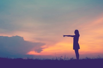 Fototapeta premium ilhouette young woman pointing forward to Dream ahead in sunset