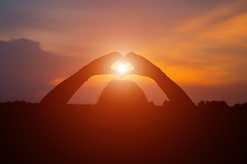 Fototapeta na wymiar silhouette of woman heart shape making of hands against at sunse