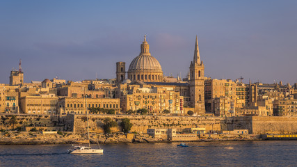 Fototapeta na wymiar Valletta, Malta - Sailboat and the famous St.Paul's Cathedral with the ancient city of Valletta at sunset