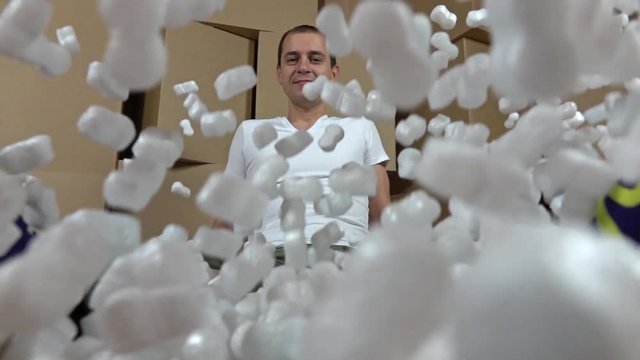 Safety, security and insurance concepts. Pouring soft polystyrene pieces onto happy man. Shockproof packaging material. Super slow motion video
