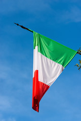 Naklejka na ściany i meble Detail of an national Italian flag with pole on a clear blue sky